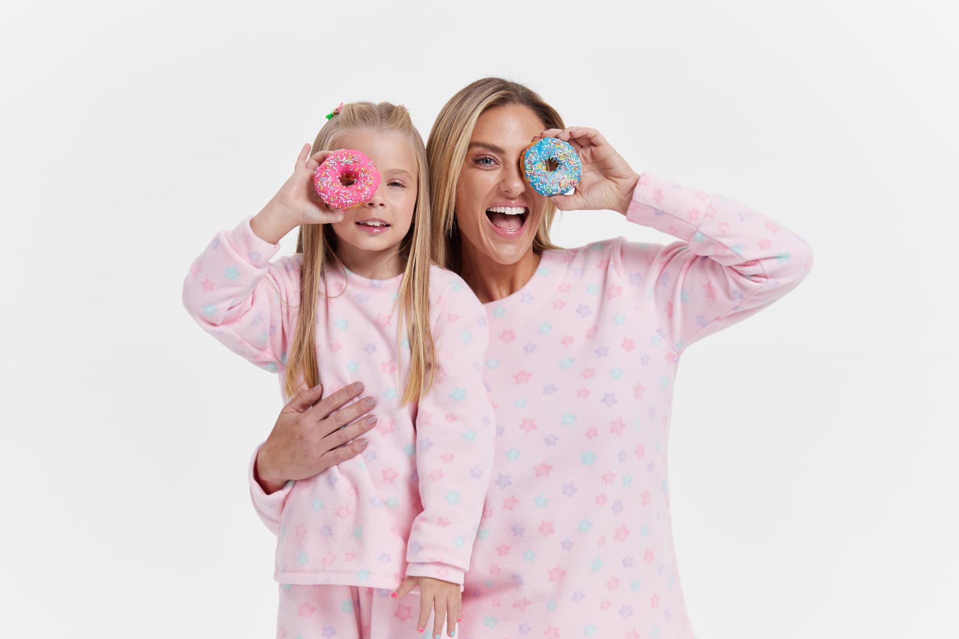 Mãe e filha brincando com donuts coloridos em fundo branco