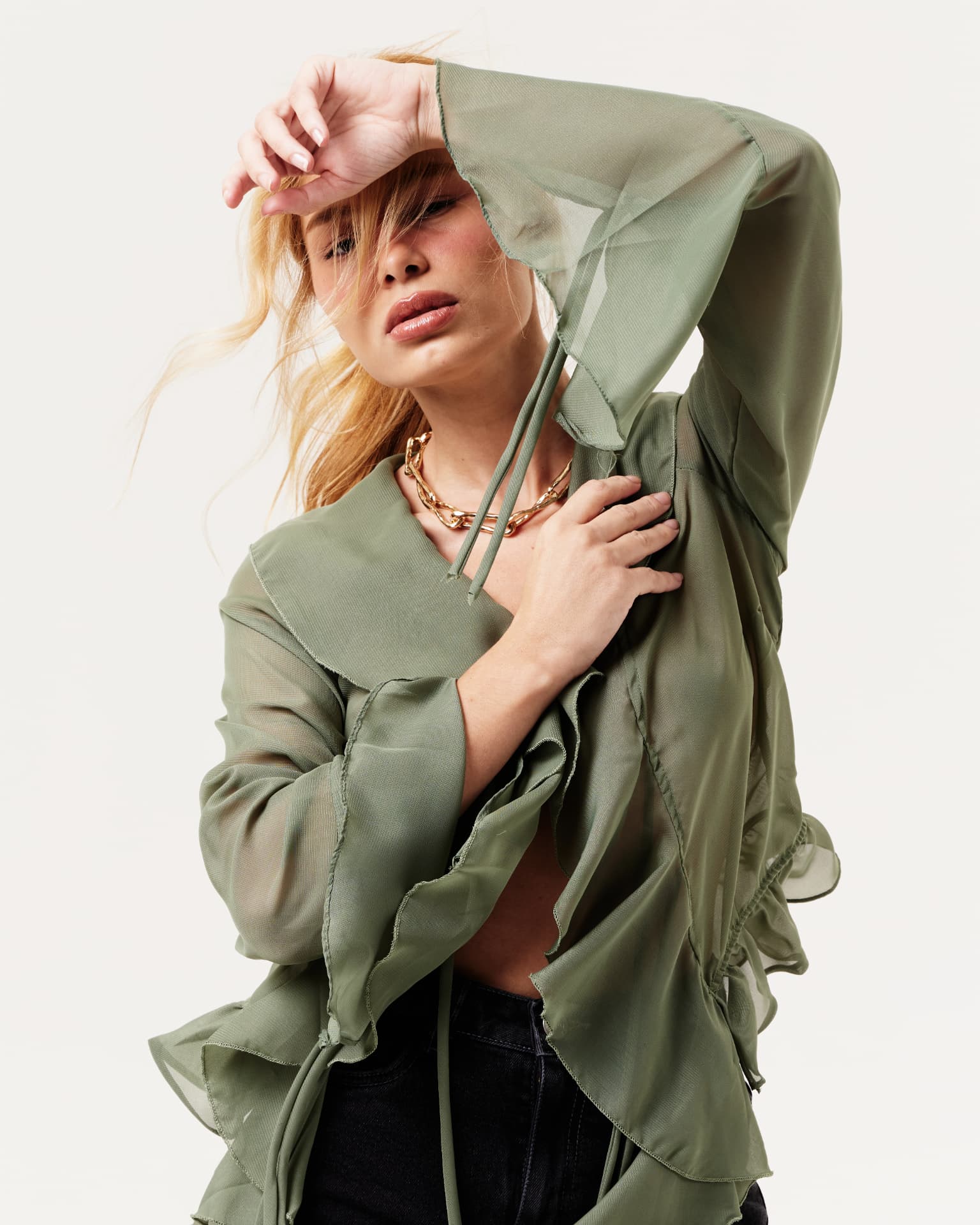 Modelo com blusa verde fluida em fundo claro
