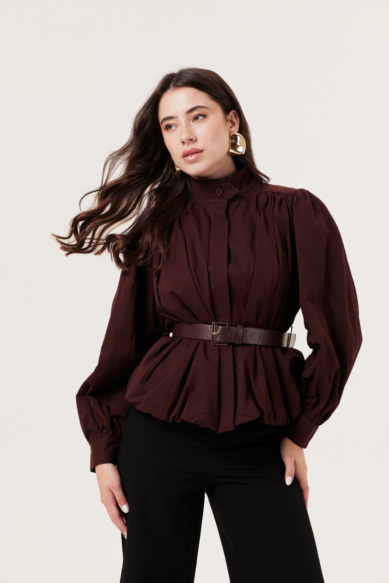 Modelo com blusa vinho e calça preta em fundo claro