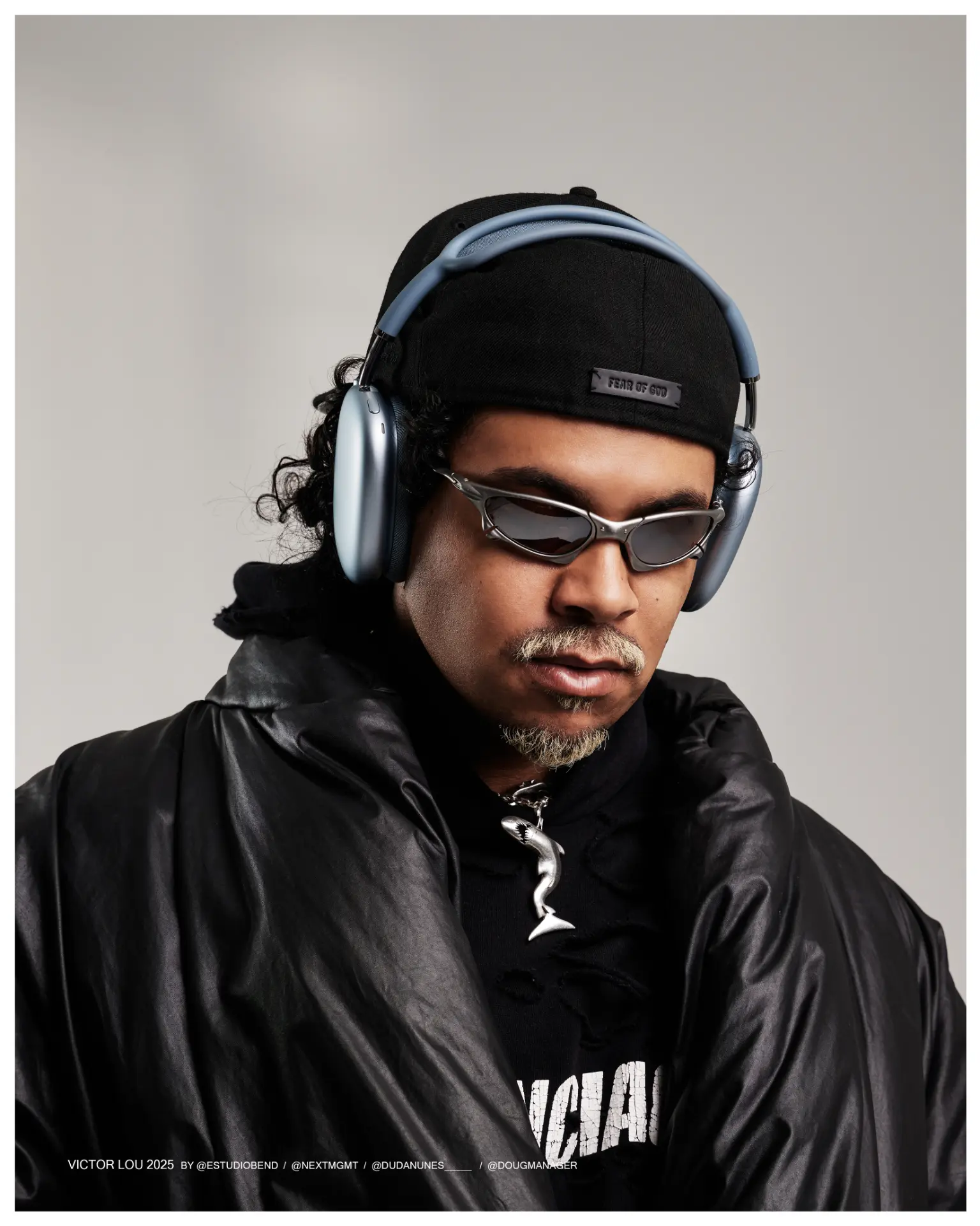 Victor Lou com fones, boné e óculos em fundo claro