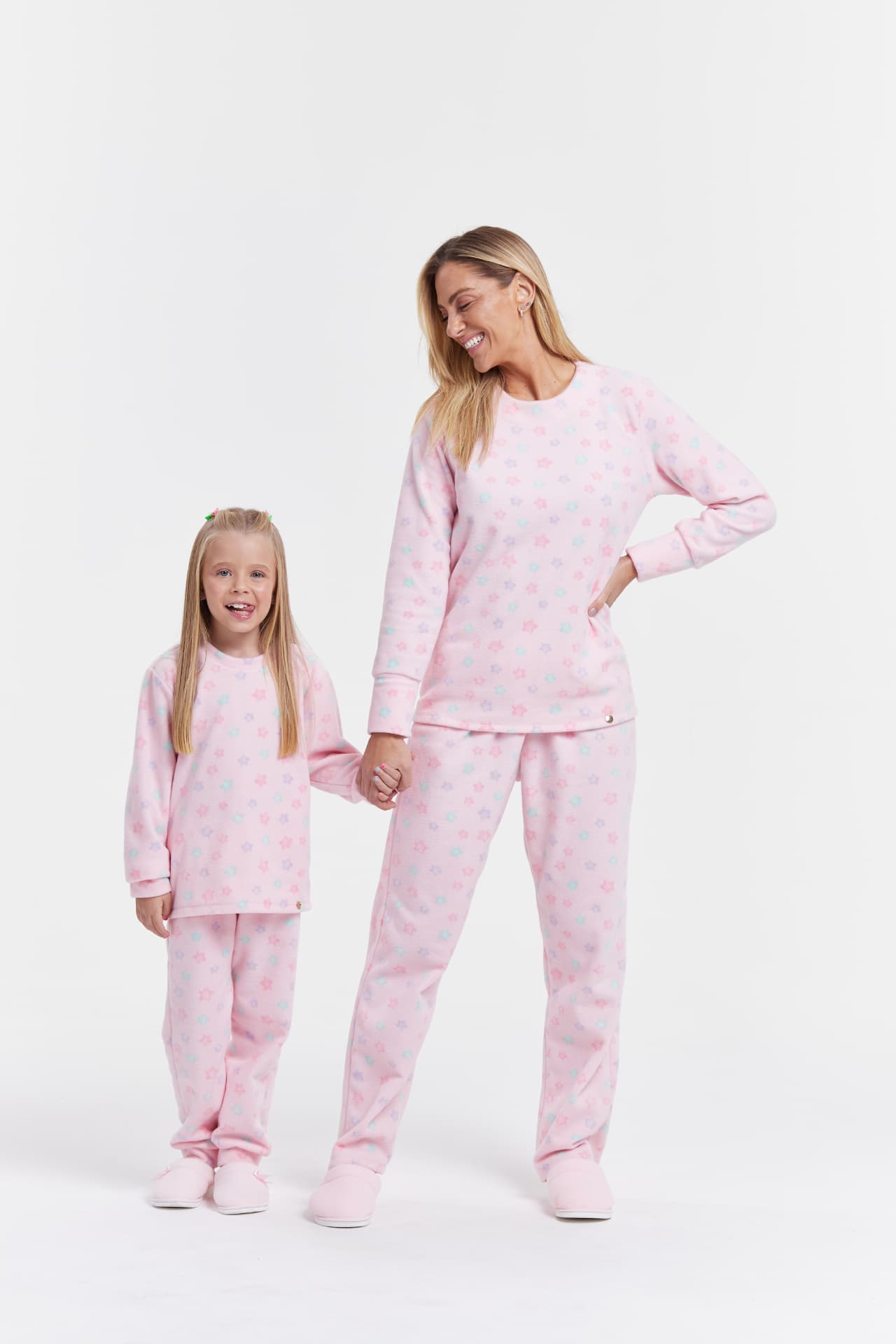 Mãe e filha com pijamas rosas de estrelas em fundo branco